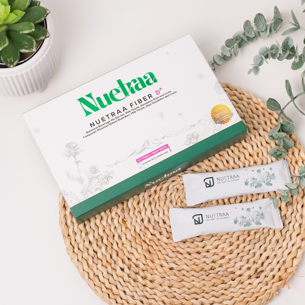 Nuetraa Fiber D+ dalam kotak putih dengan sachet, dipamerkan bersama sachet di atas alas rotan